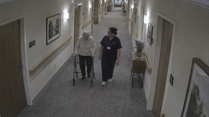 High-angle care facility camera view showing normal corridor activity